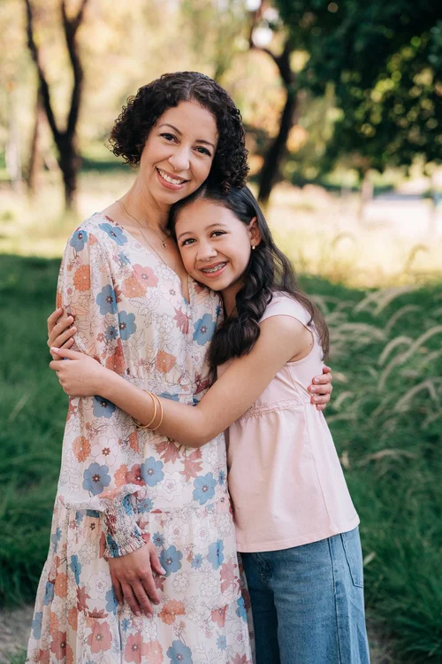 Mom in a floral dress hugging her older daughter at Jeffrey Open Space Trail in Irvine