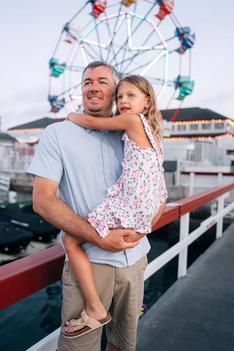 A father holding his daughter during a day in the life session on Balboa Island