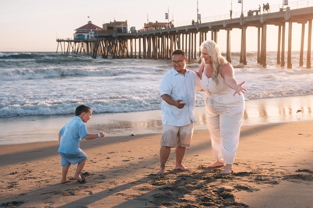 The boy veering off toward the water, head down, while his parents laugh and reach after him