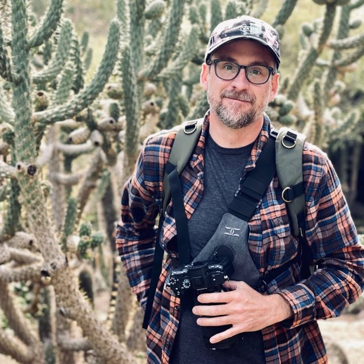 Daniel Wesley, family photographer based in Anaheim Hills, Orange County, holding his camera in front of a stand of cactus