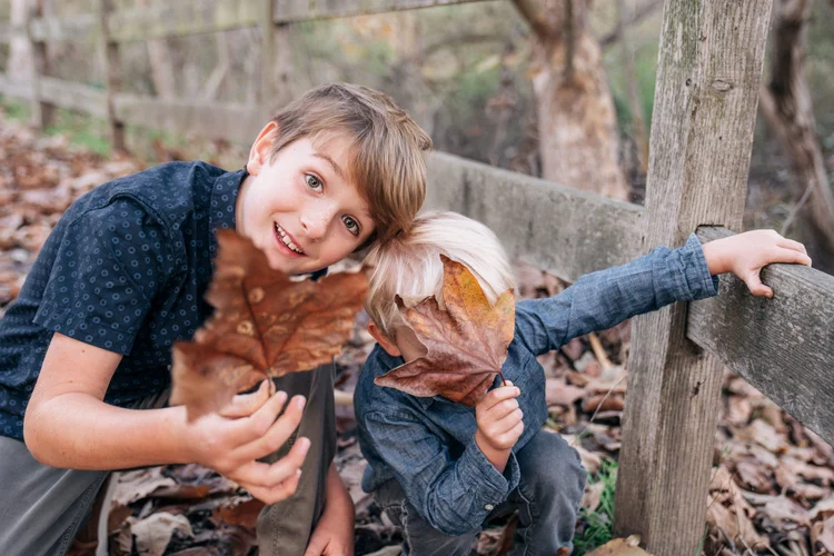 The two boys being silly with fallen leaves