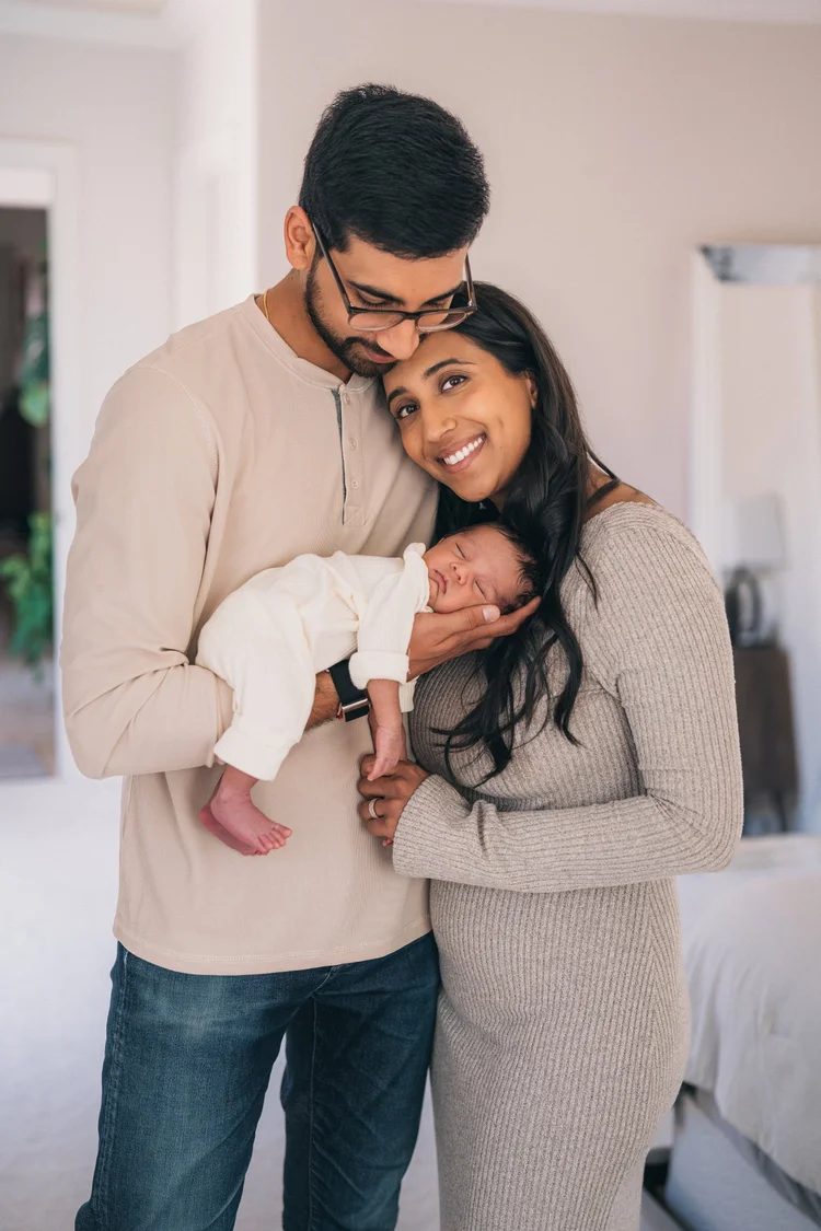 New parents holding their sleeping newborn at home during an in-home newborn session