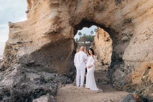 An expecting couple standing inside a sea cave arch at Treasure Island Beach in Laguna Beach