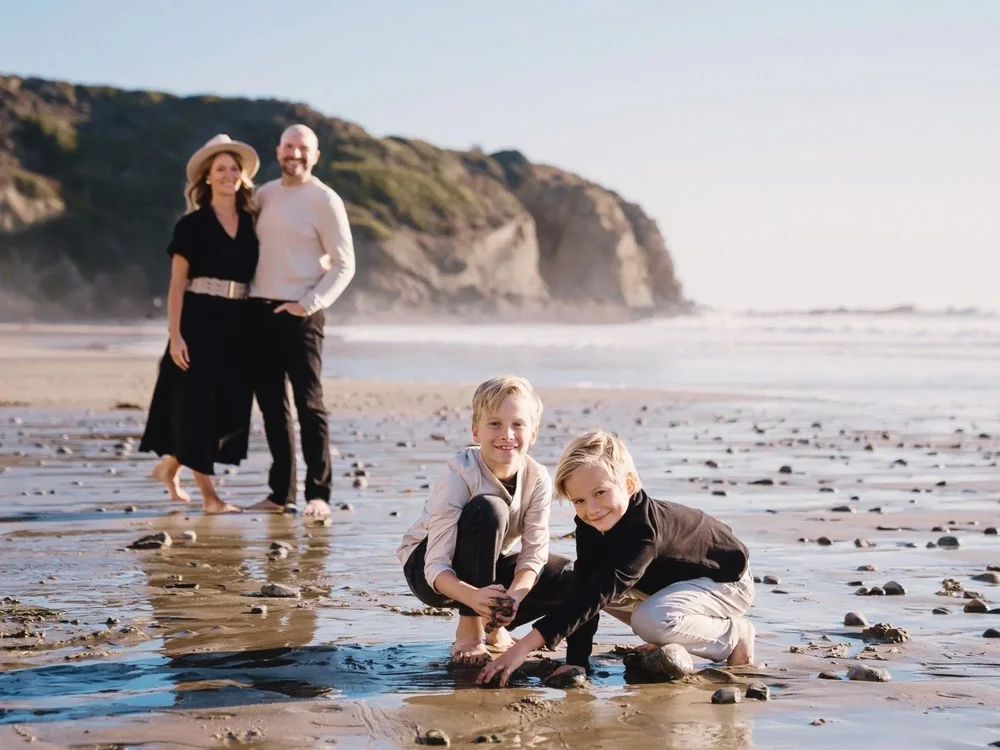 Two boys crouched at the waterline during an Orange County beach family session