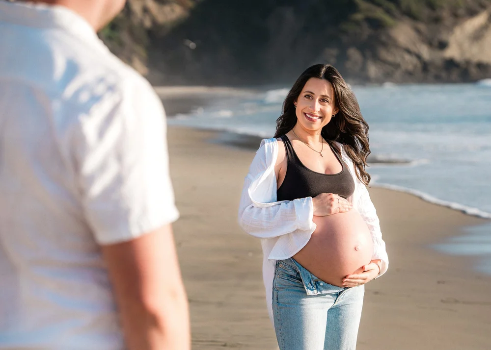 An expecting couple on the beach at golden hour during a maternity session in Orange County