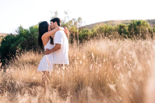 A couple kissing in the tall golden grass on the hills at Quail Hill in Irvine