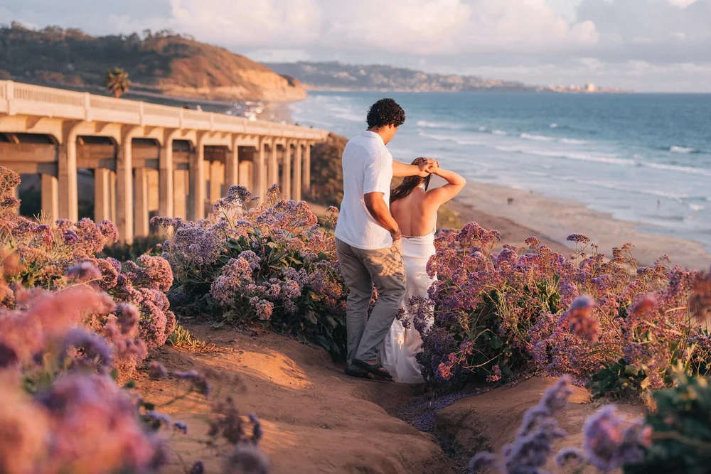 Anais and Quinn walking through wildflowers on the bluffs above the beach