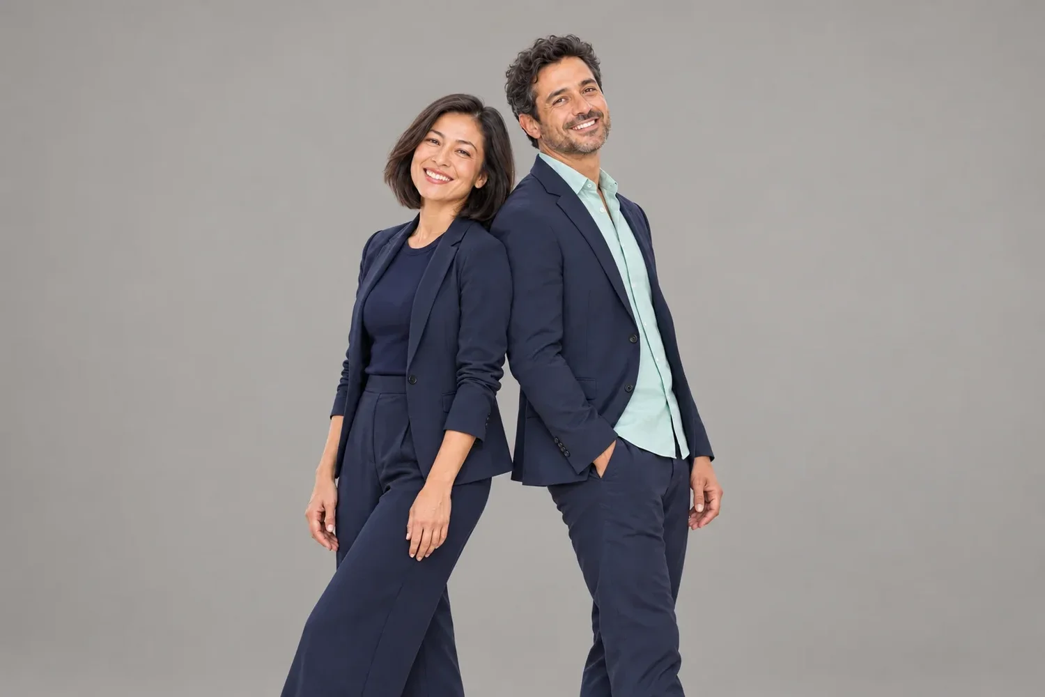 Two adults in navy business attire against a plain gray studio backdrop