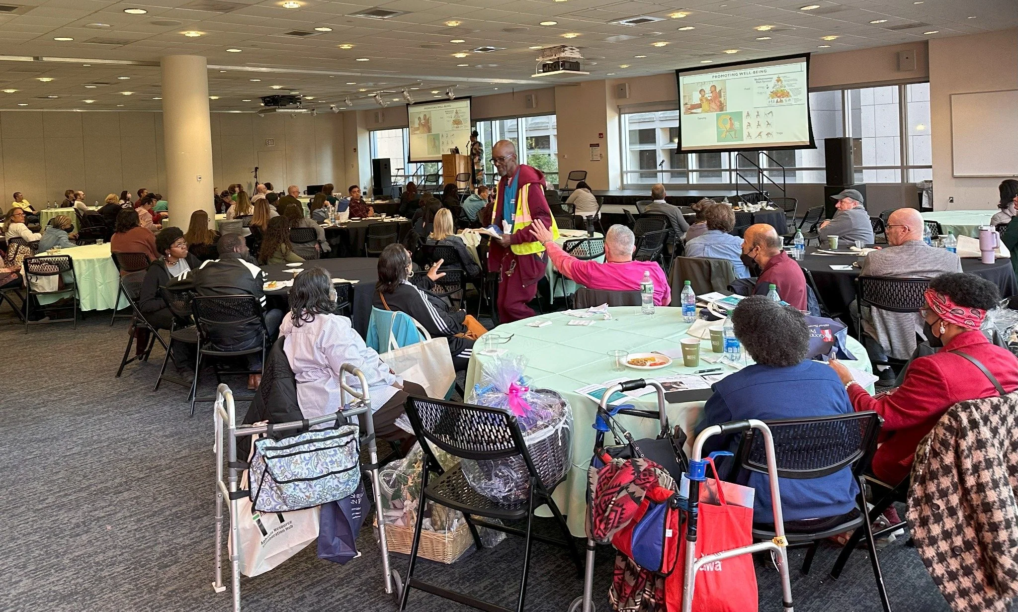 Wide view of a ROSA gathering with participants, tables, and a presentation area