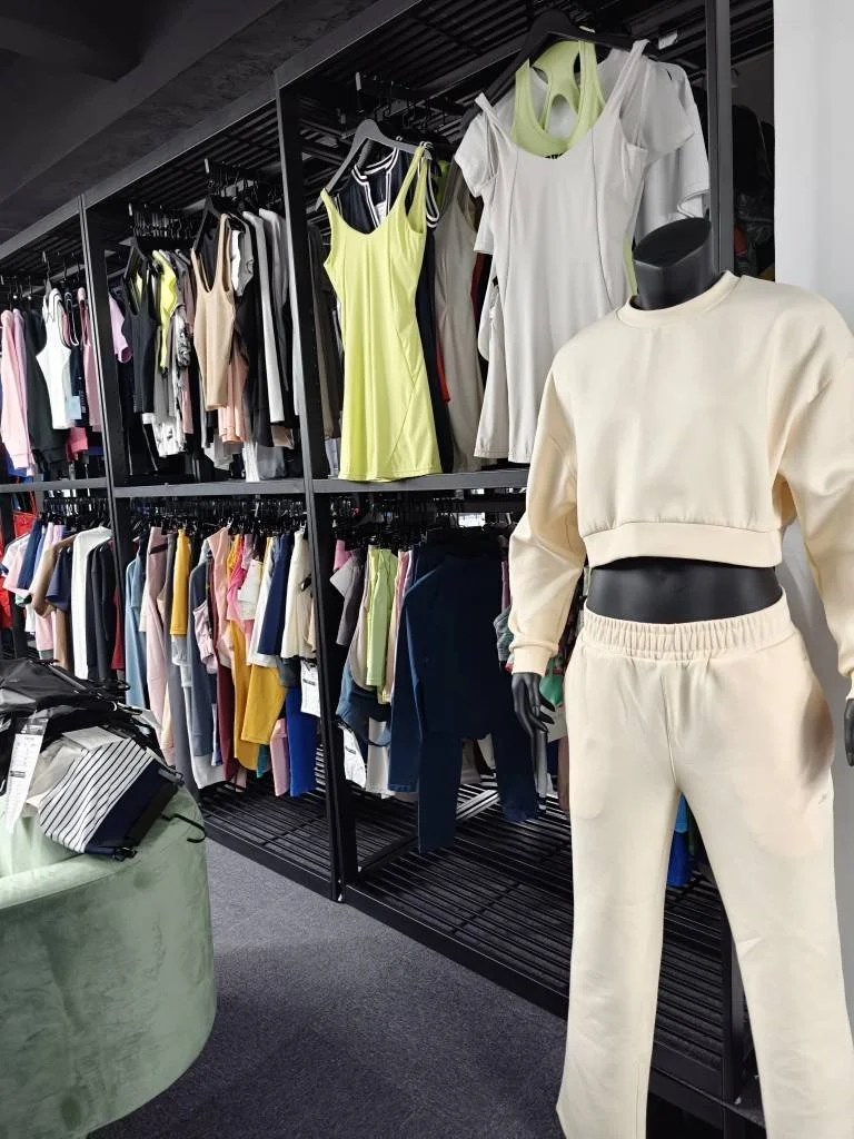 Cream sweatshirt and pants on a mannequin beside racks of apparel samples