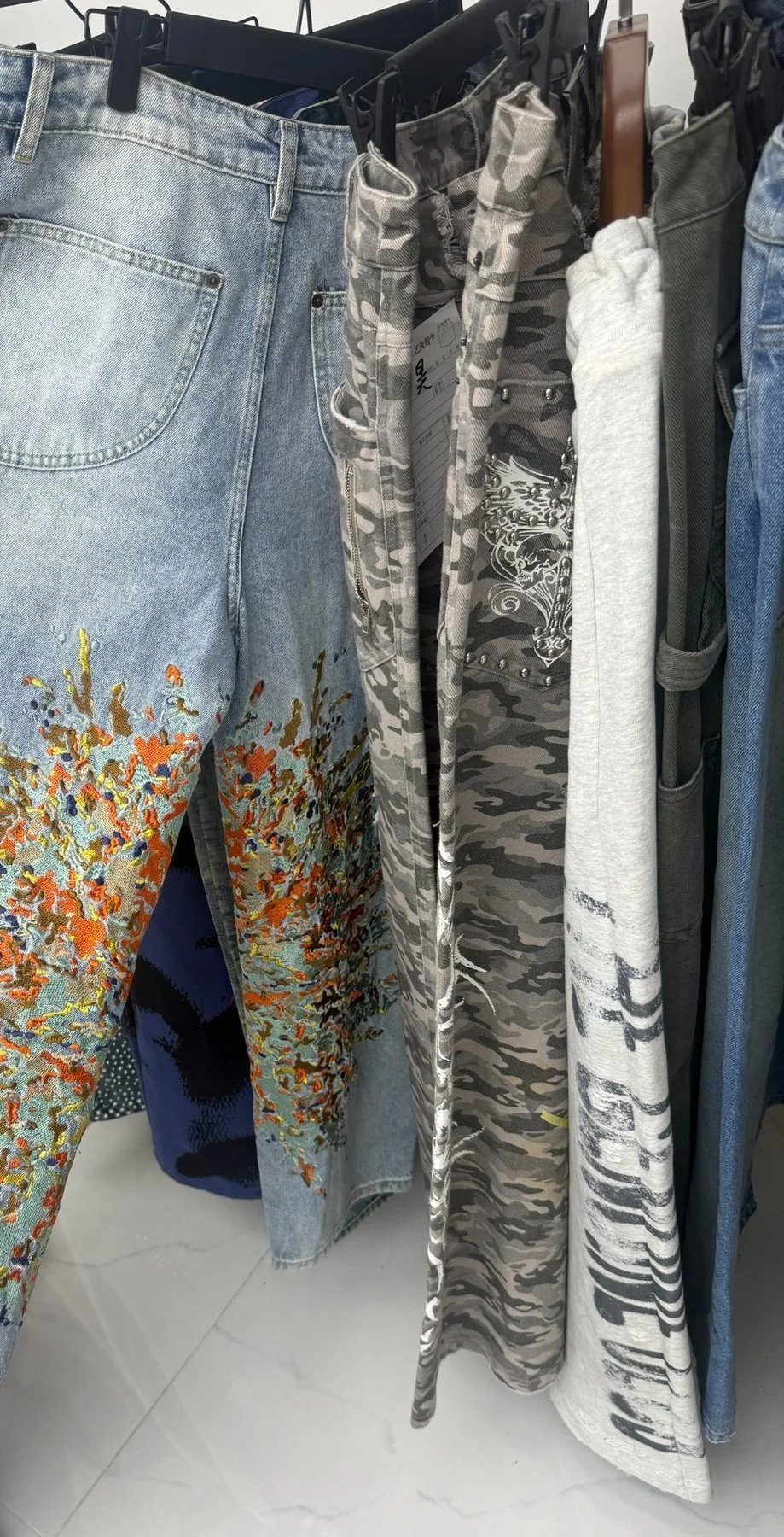 Denim and printed trouser samples with embroidery and decorative hardware