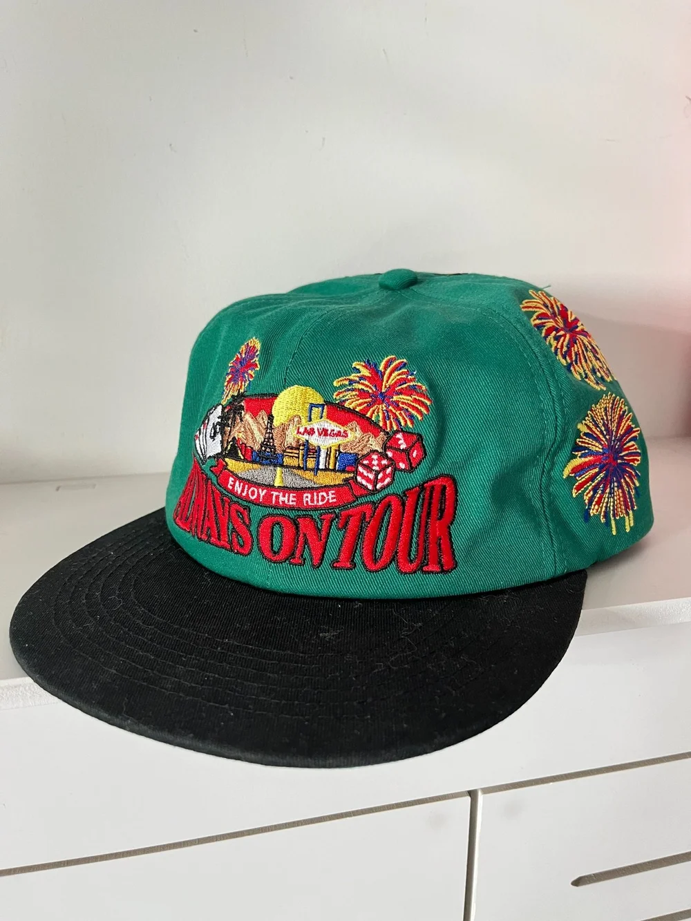 Green cap with colorful embroidery and a contrasting black brim