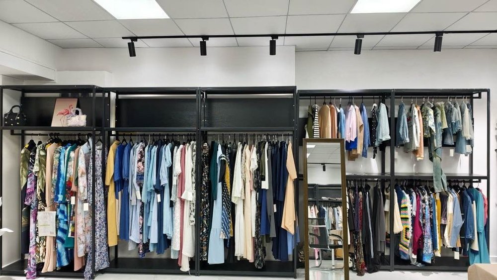 Clothing sample racks displaying shirts, dresses, jackets, and other garment styles