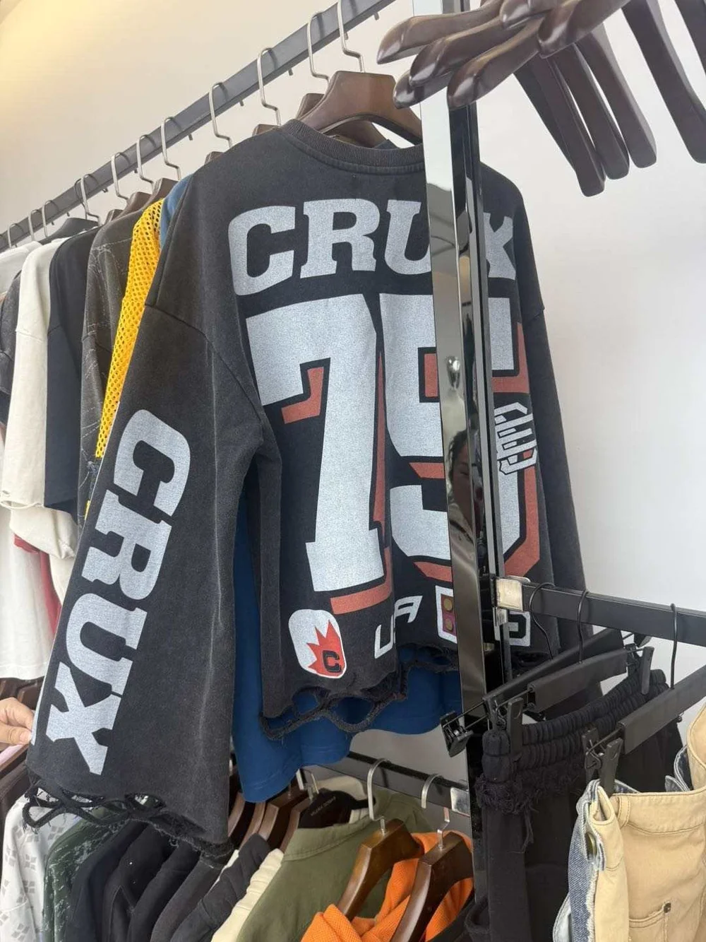 Dark graphic long-sleeve sample with a large number print and sleeve lettering on a rack