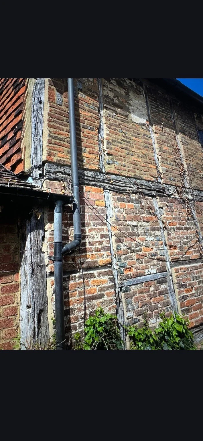 Timber-framed brick exterior before work, with weathered timber and exposed masonry