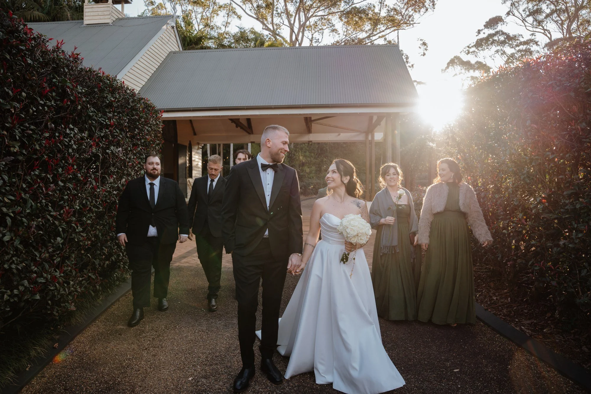 Livia and David walk hand in hand with their wedding party through Shambala Estate’s gardens, with the Chapel behind them.
