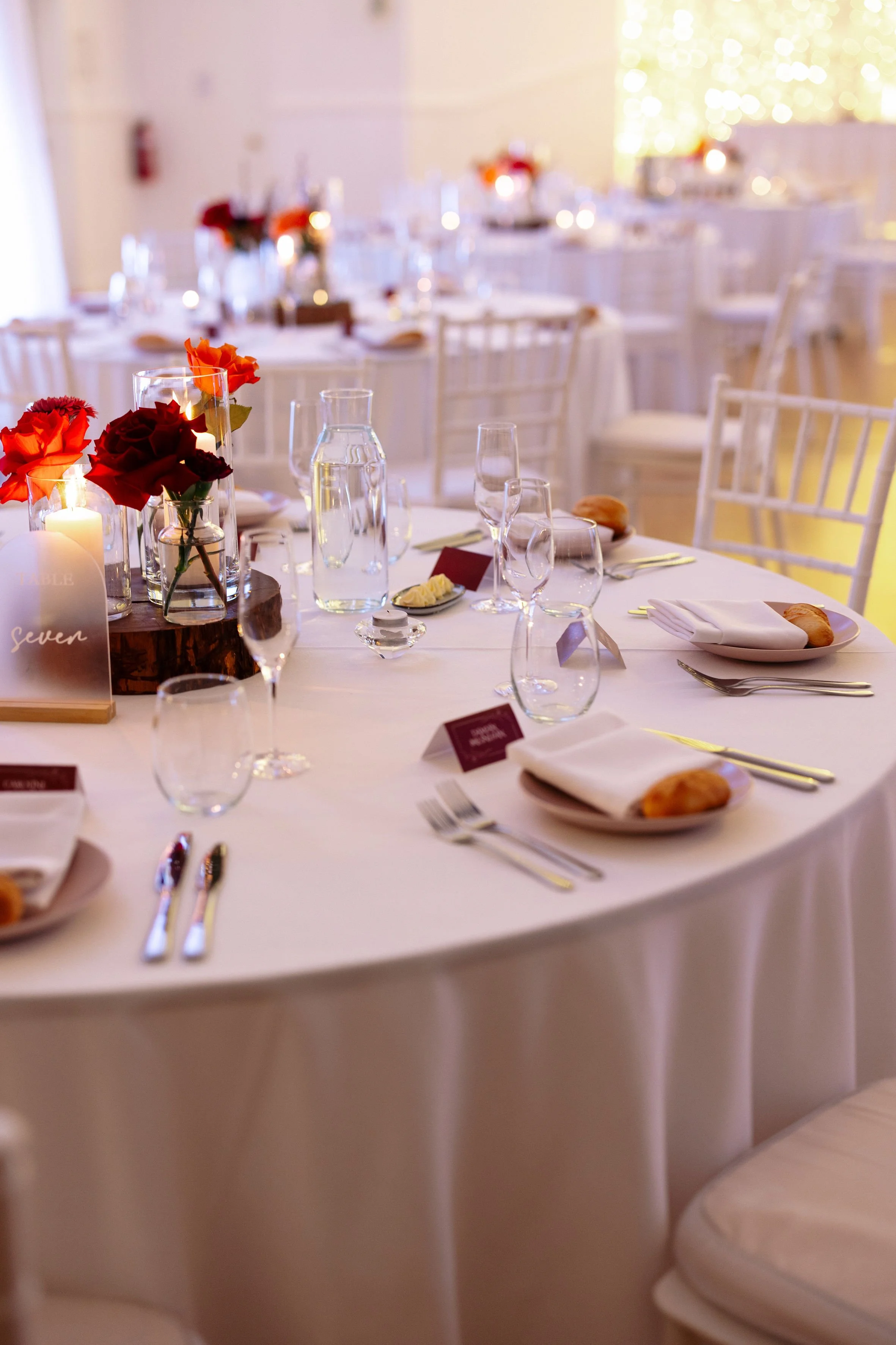 Flowers, table stationery and glassware arranged for a Shambala Estate wedding reception