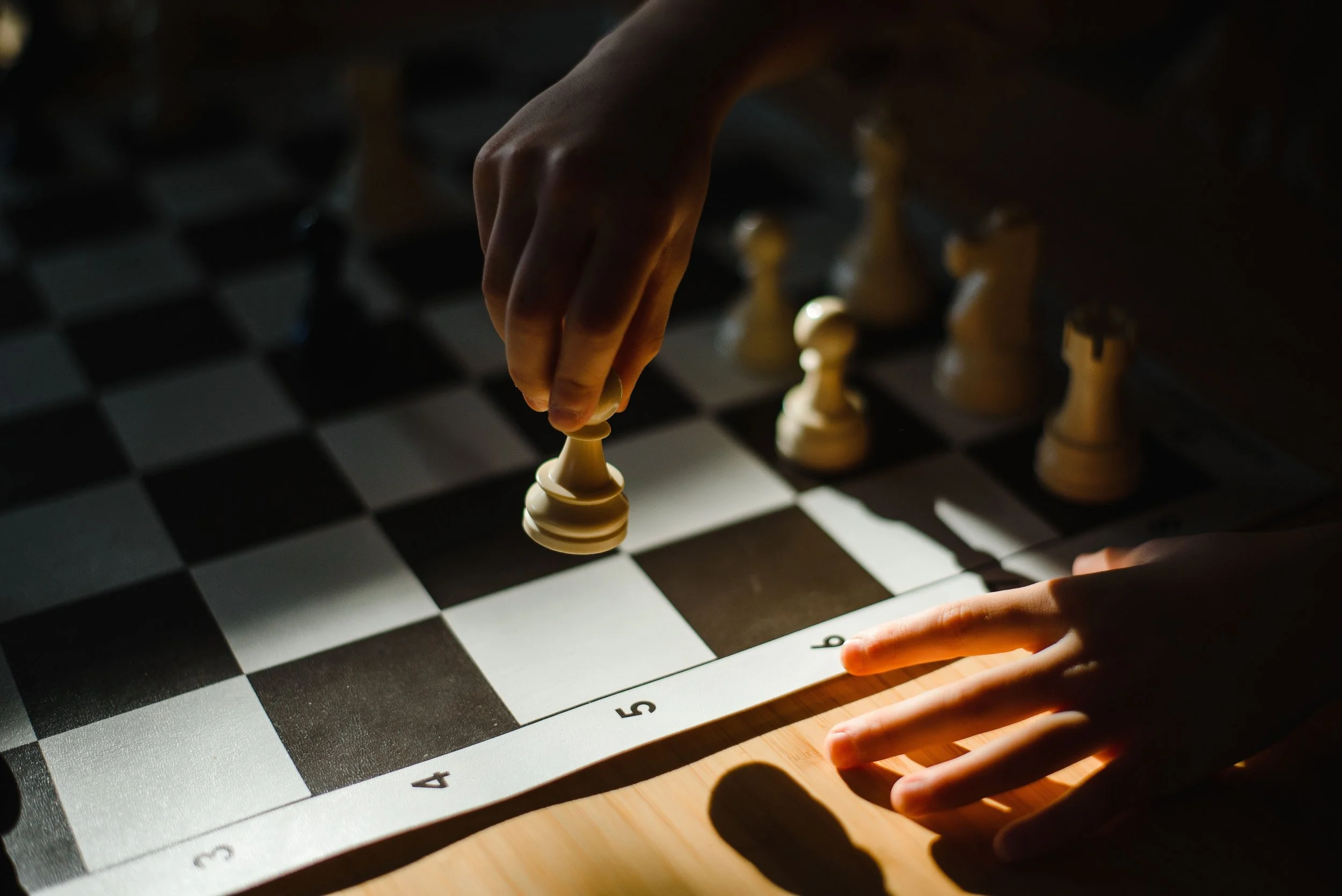 A child's hand moving a plastic chess piece on a flexible tournament-style board