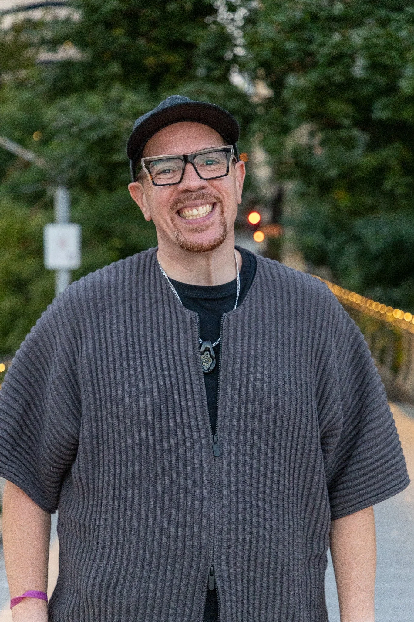 Sean Goode smiling outdoors, wearing glasses and a dark cap.