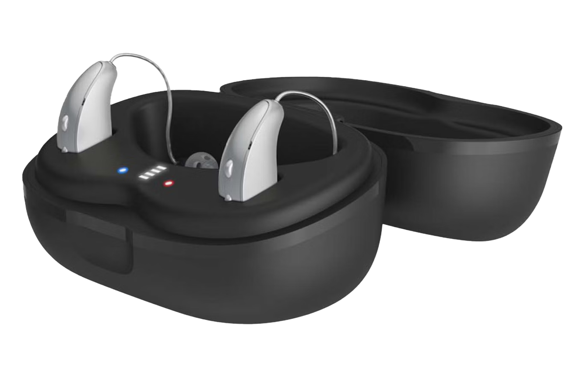 Silver hearing aids resting inside a black charging case