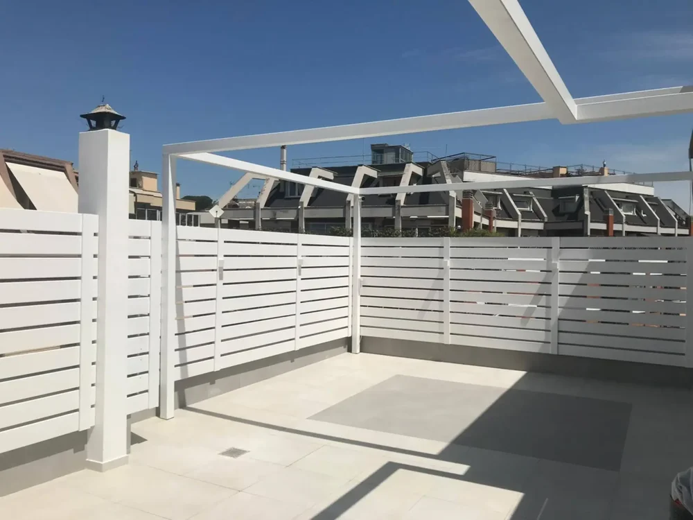 Un grande giardino pensile con ampi pannelli grigliati in alluminio bianco lungo il perimetro.