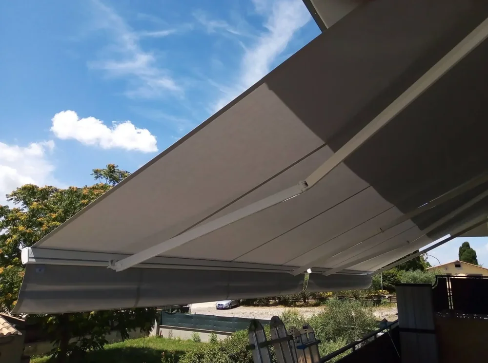 Una veranda con tenda a bracci protettiva di colore scuro realizzata in tessuto Tempotest.