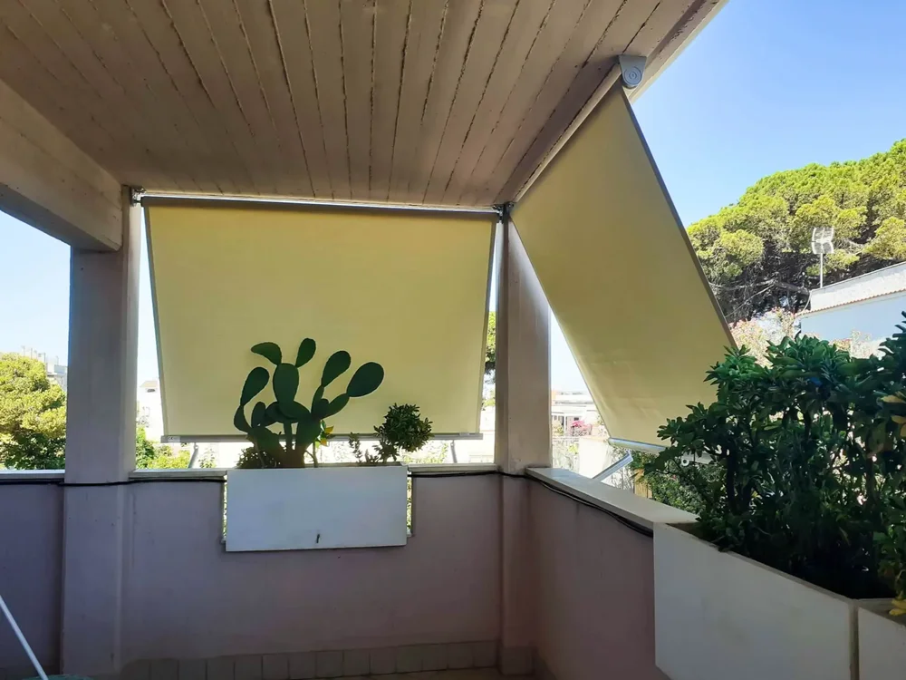 All'interno di un balcone di medie dimensioni con piante in vaso, protette da tende gialle.
