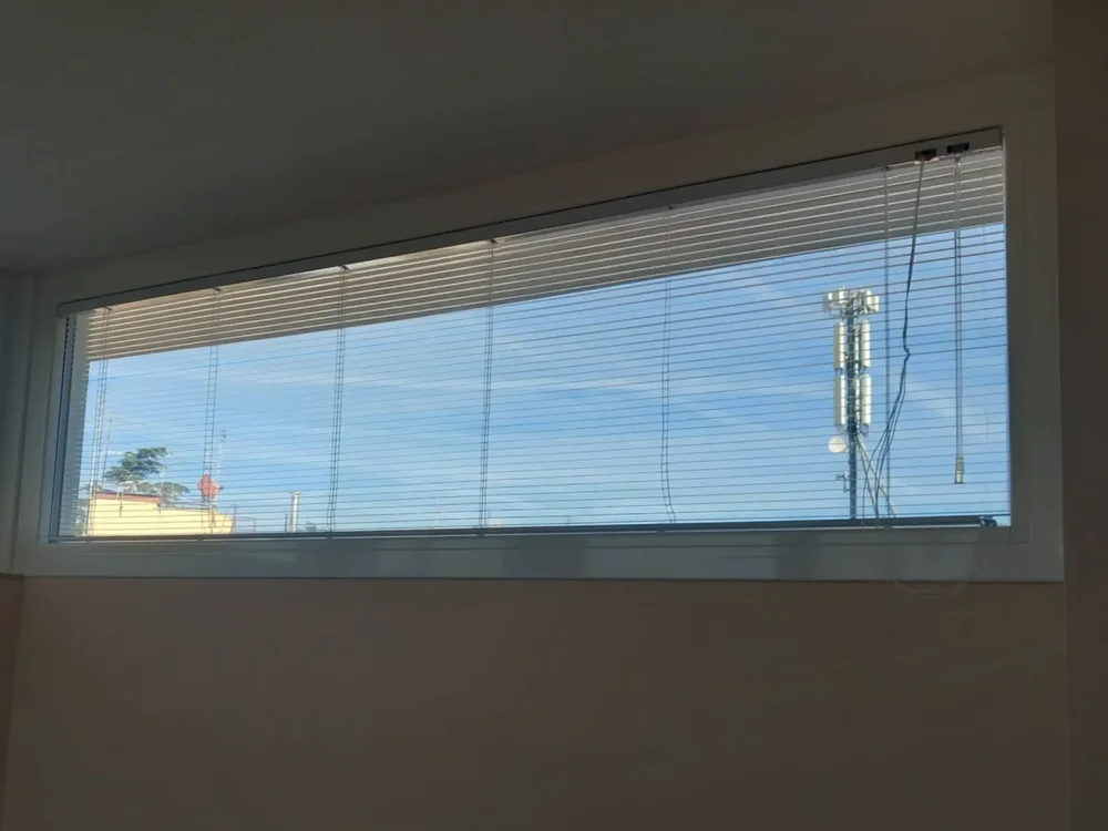 Tenda da sole a cappottina a strisce blu e bianche in PVC impermeabile, installata sopra l'ingresso di una casa.