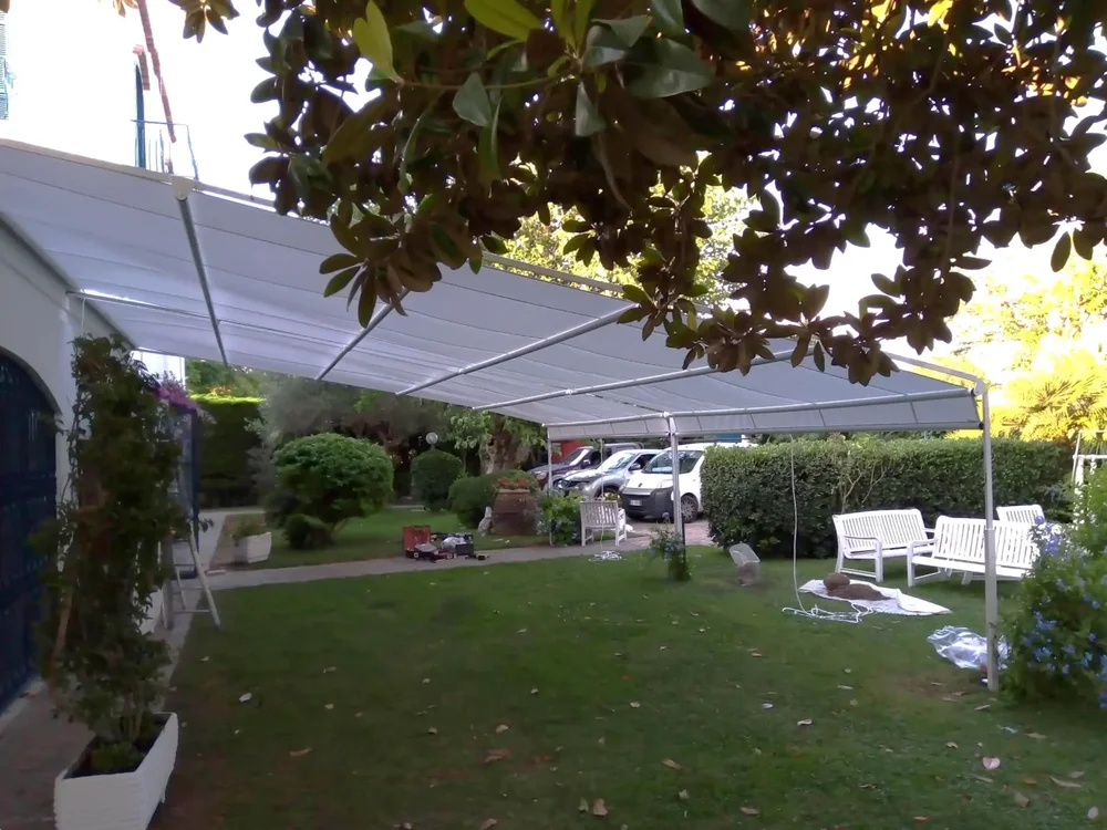 Una tenda a capanno molto grande che copre il prato davanti a una casa.