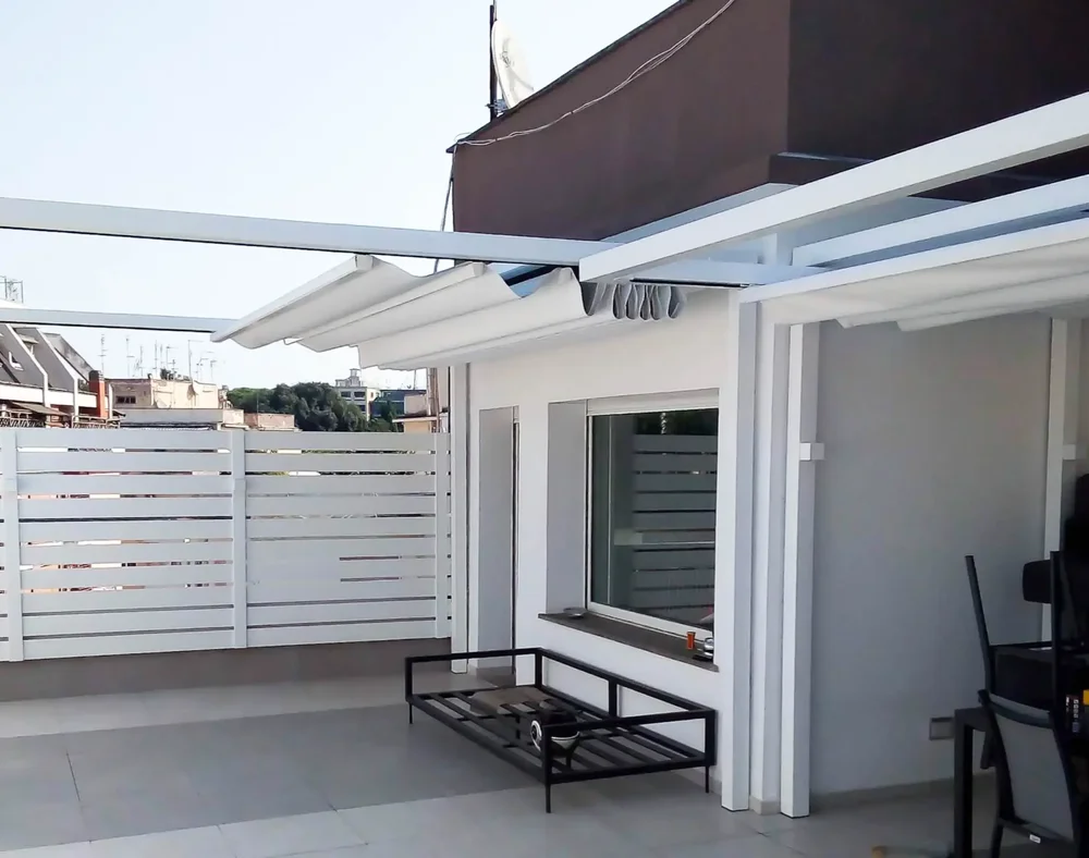 Pergotenda elettrica bianca installata su un terrazzo, mostrata con la copertura in tessuto flessibile Tempotest completamente retratta.