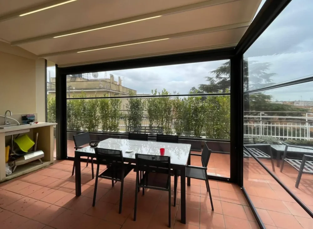 Terrazza a Roma con zona pranzo protetta dalle nostre chiusure laterali in PVC Cristal trasparente.