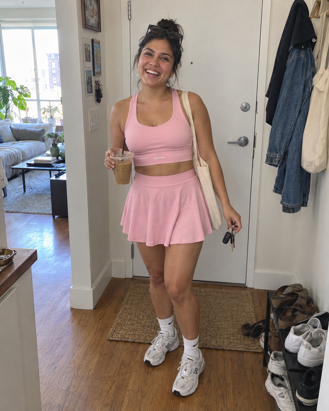 Casual doorway snapshot of a woman in a pink Fieldtime sports bra and skirt