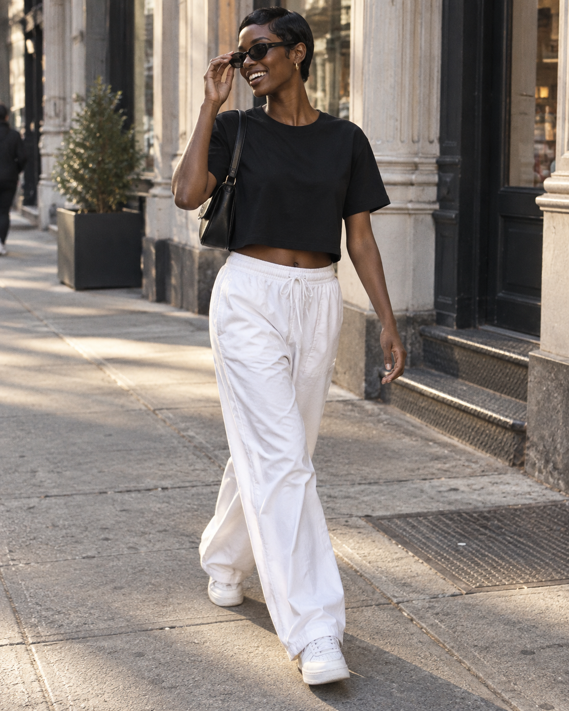 Woman wearing the black Fieldtime crop tee with sunglasses on a city sidewalk