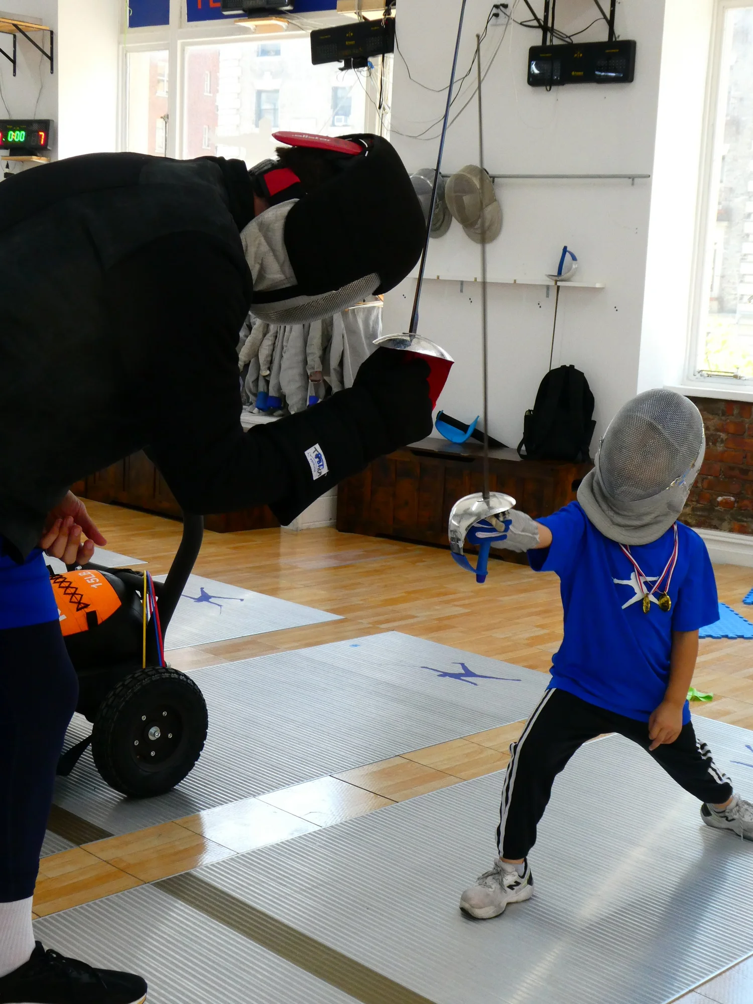 A young fencer in full gear lunging during a fun match with a TMFC coach