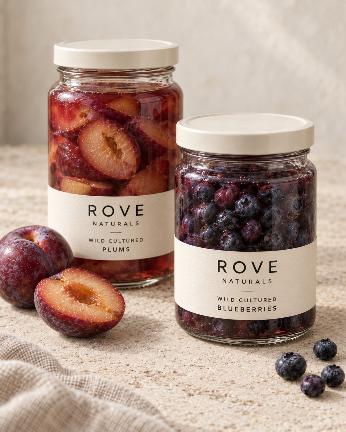 Rove wild-cultured plum halves and blueberries in glass jars with natural fruit texture and soft light.