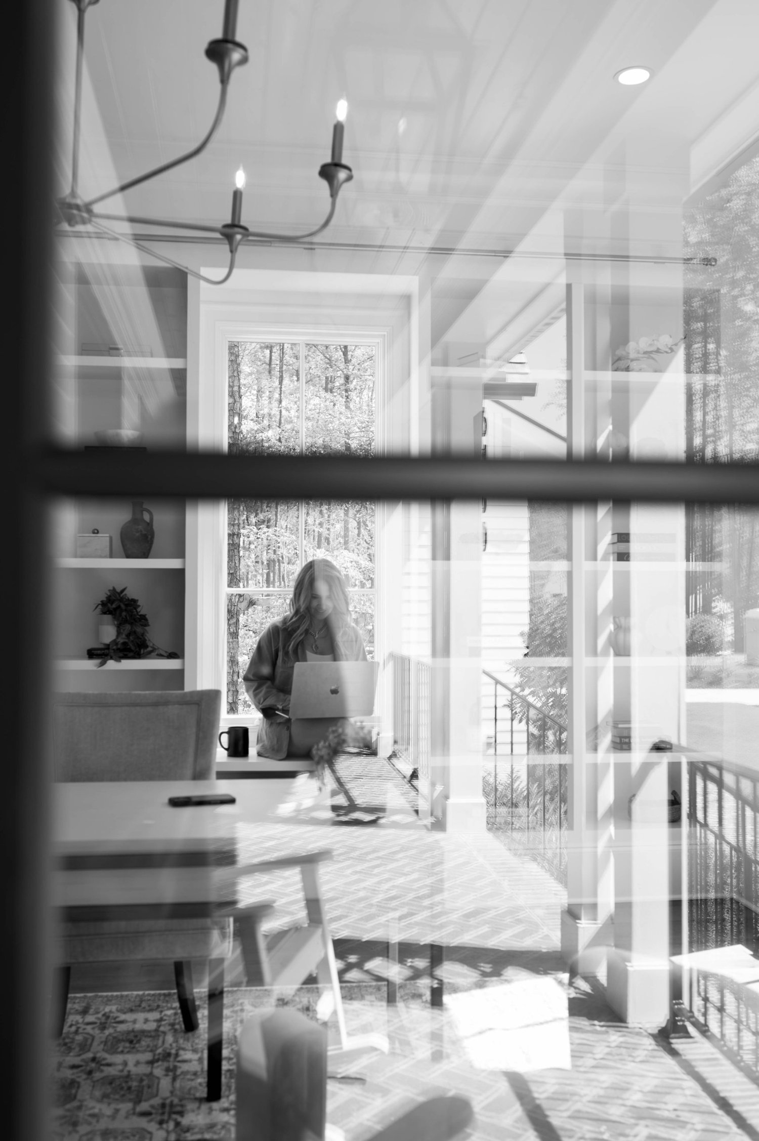 Jessie at her laptop, seen through a window