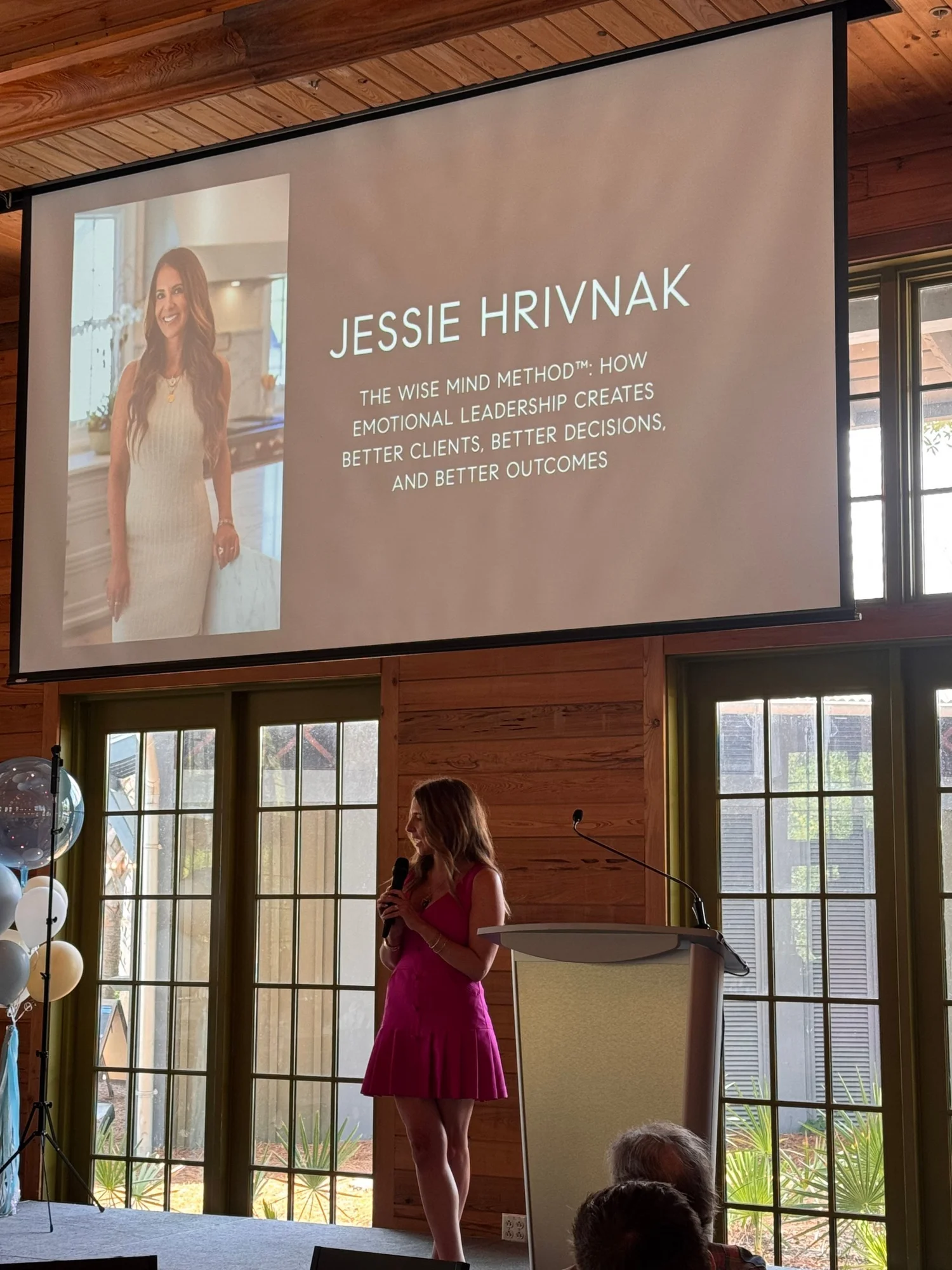 Jessie onstage at Compass 30A beneath her session title slide
