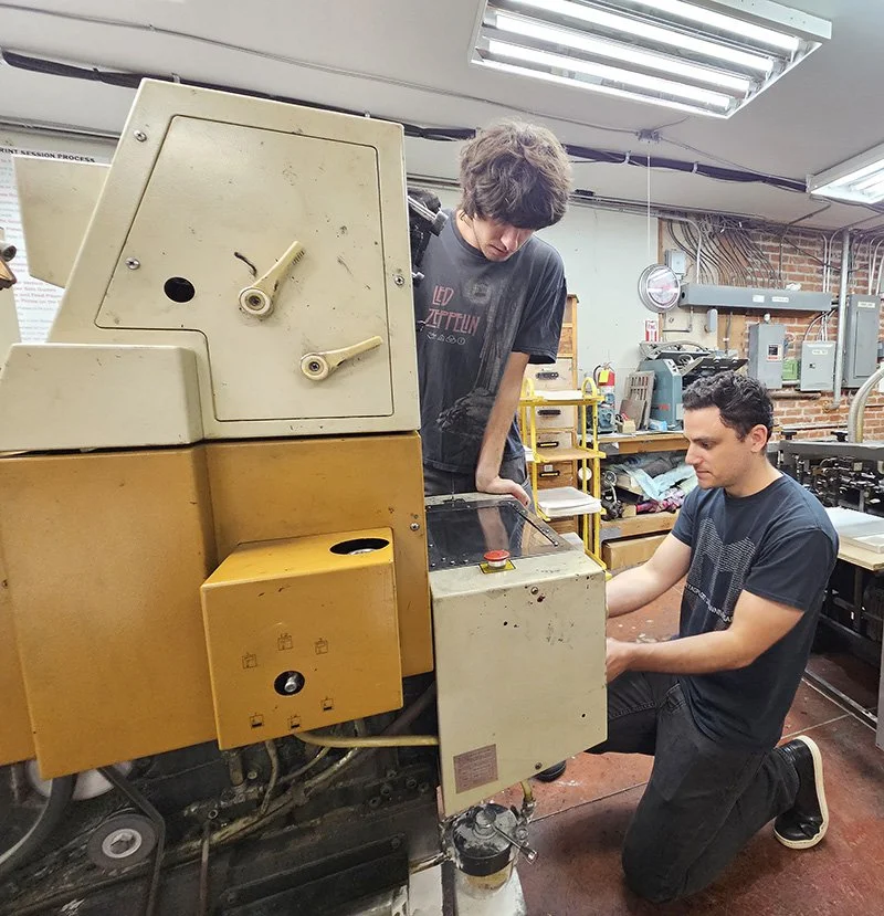 Two BAAP volunteers prepare to print on an Ryobi two-color offset press