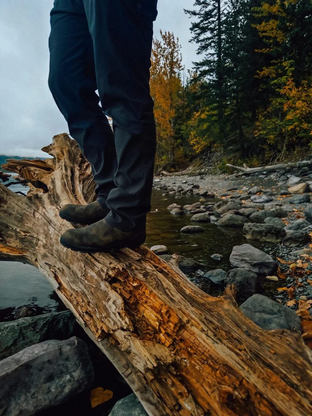 Boots on a driftwood log by a creek in fall