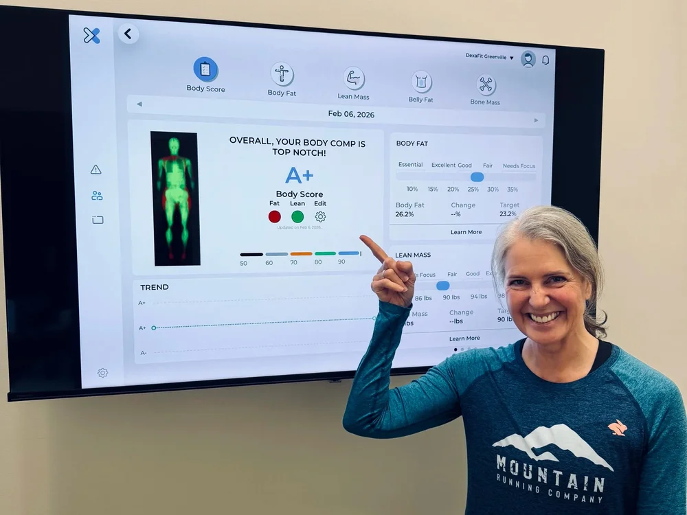 A smiling client pointing to her DEXA results on the screen at DexaFit Greenville