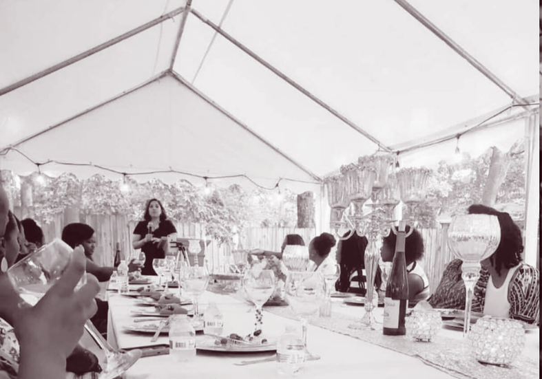 Lissette speaking to women gathered at a dinner under a tent