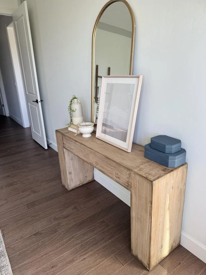 Reclaimed wood console table with an arched brass mirror