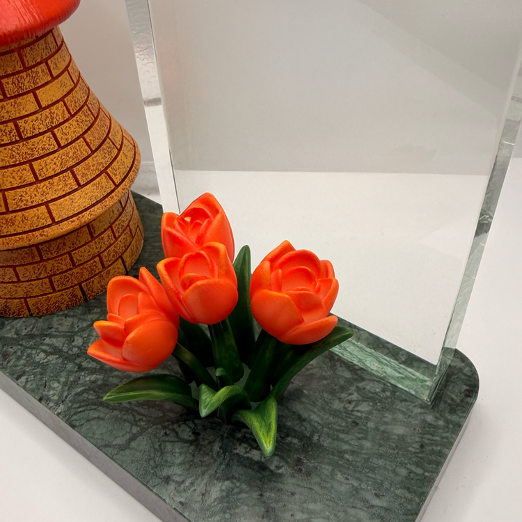 Close view of hand-painted resin flowers beside a windmill sculpture