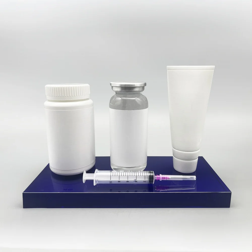 Miniature pharmaceutical packaging and product forms on a blue commemorative base