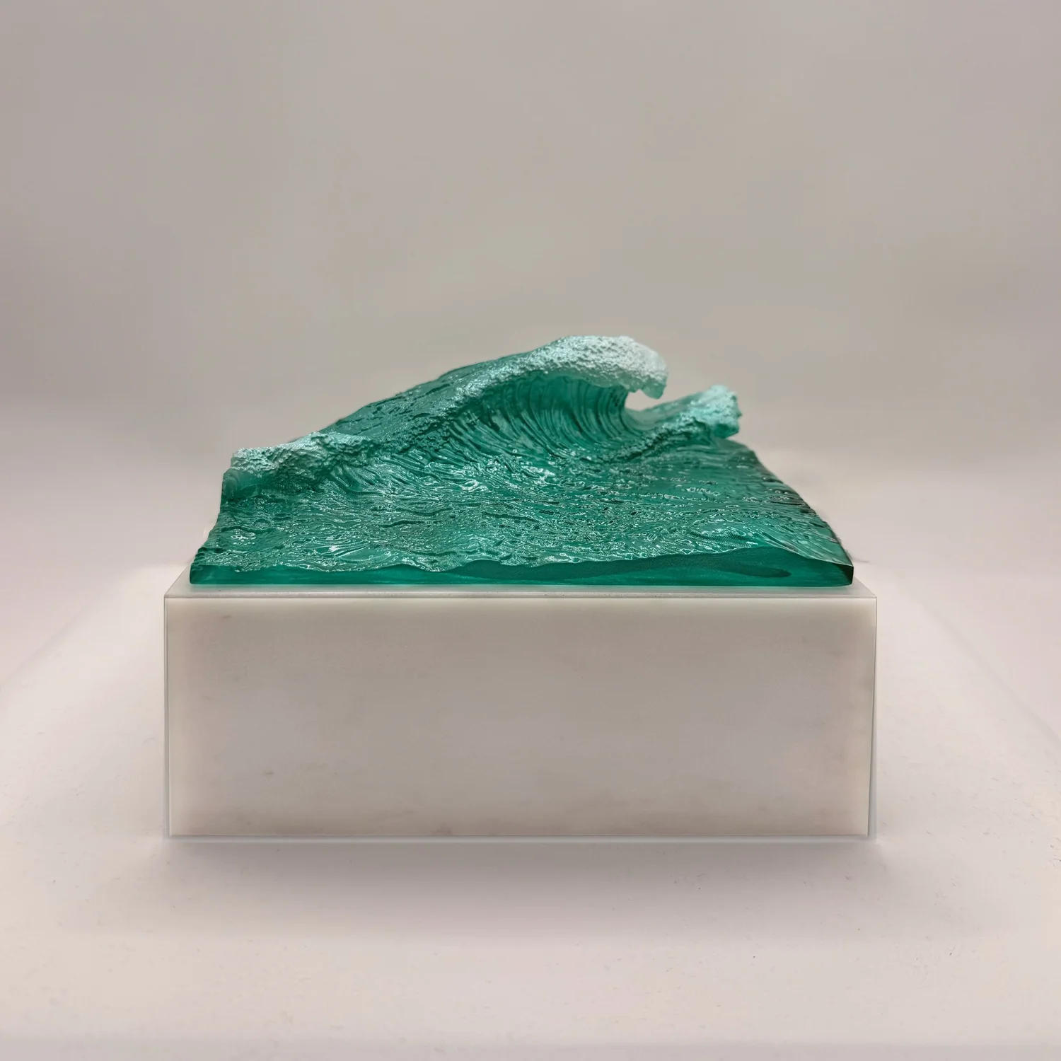 Green ocean wave sculpture on a rectangular presentation base