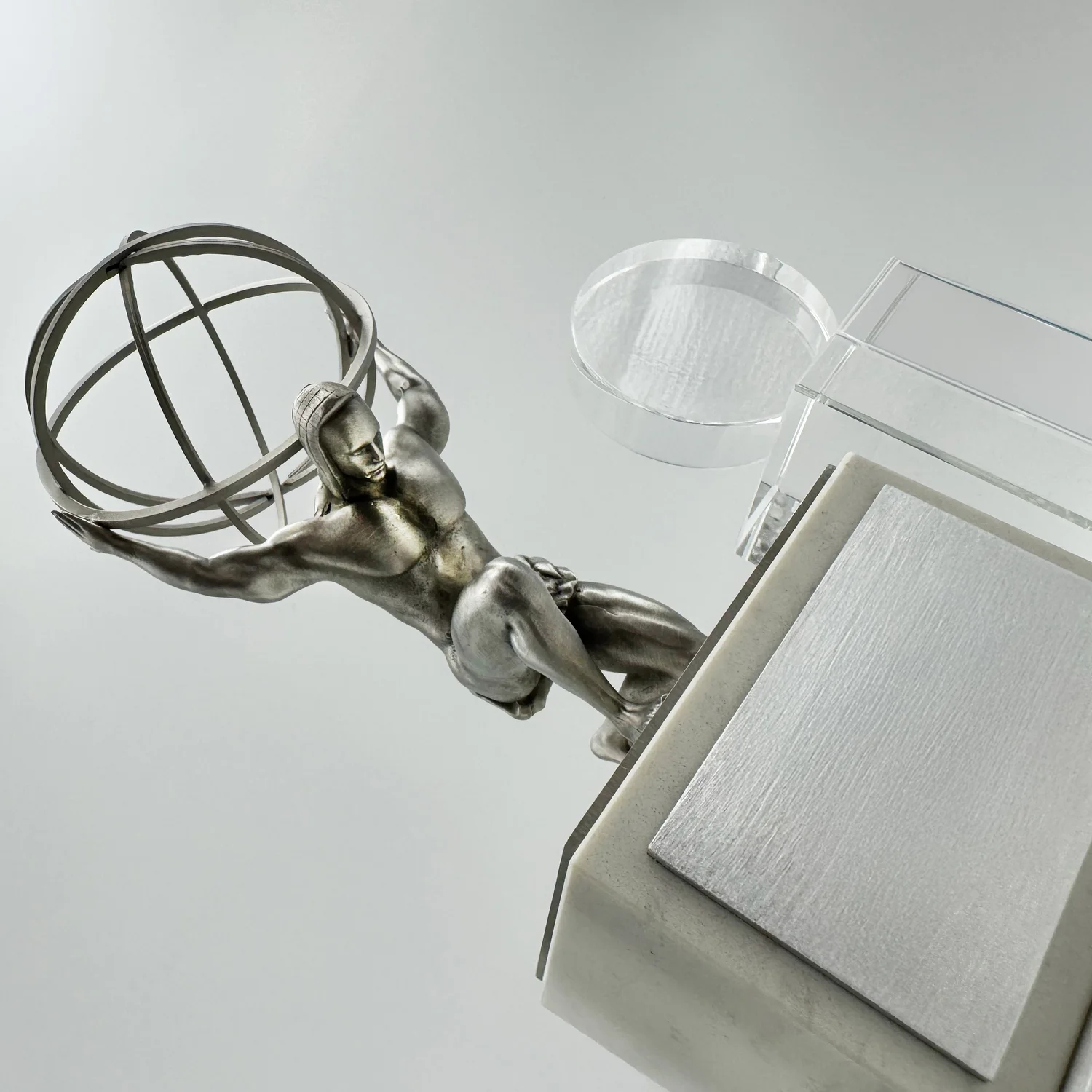 Close view of a metal Atlas sculpture beside a clear award component