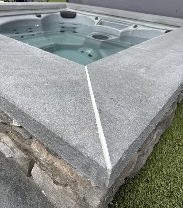 Continuous light sealant at a stone spa-coping corner.