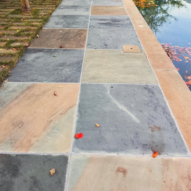 Joint detail along multicolor stone paving beside a pool.