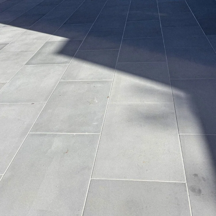 Light joint lines across gray paving, with a diagonal shadow.