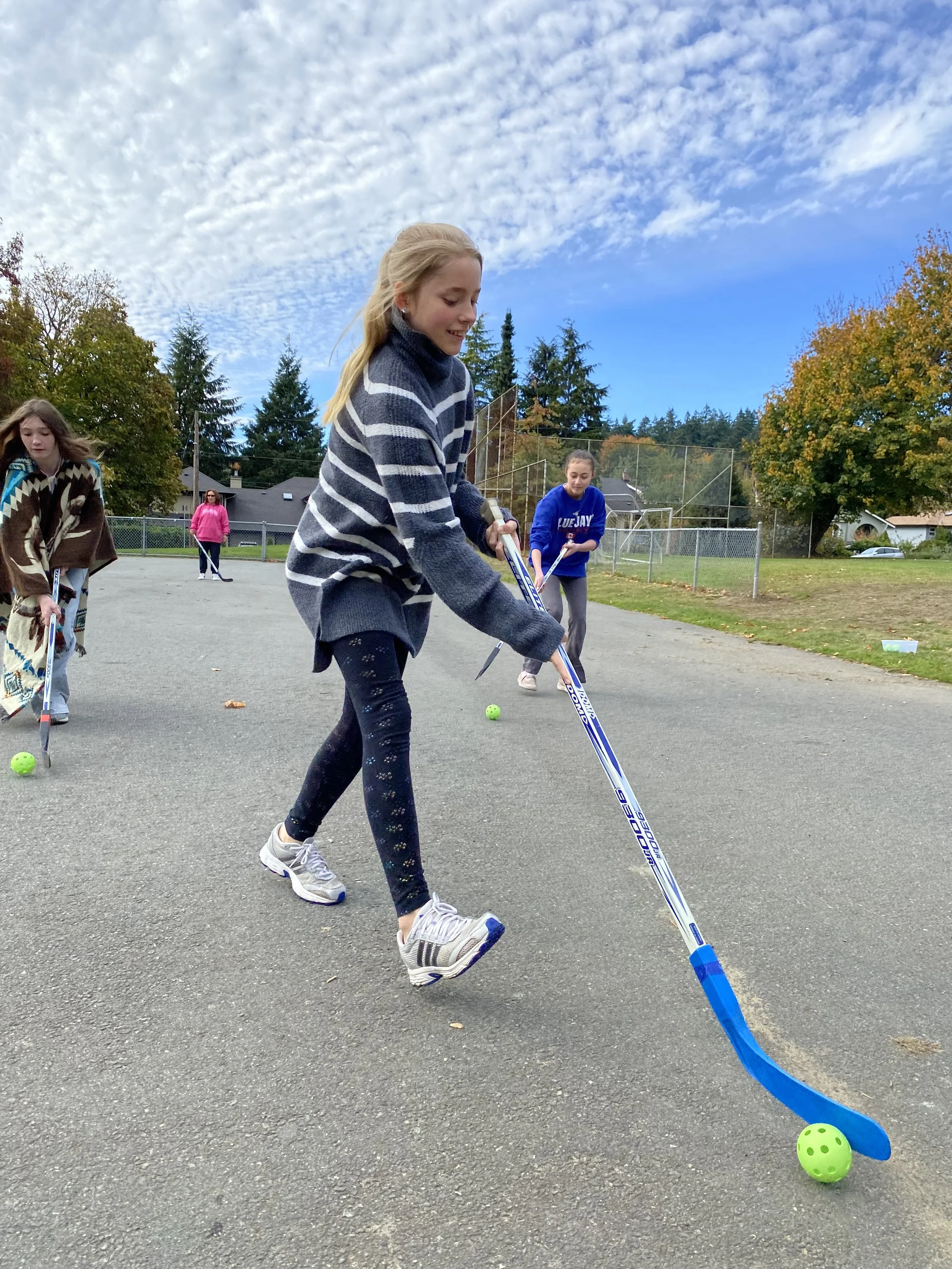 Students exercising outside together by playing street hockey